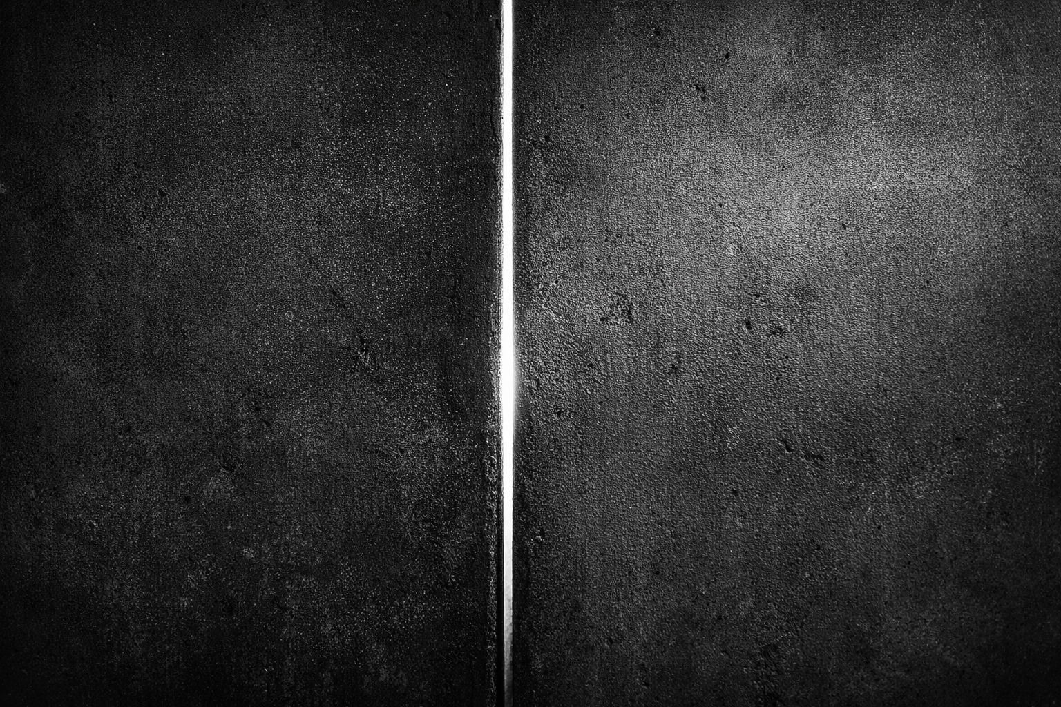 n muro scuro con una sottile linea di luce al centro